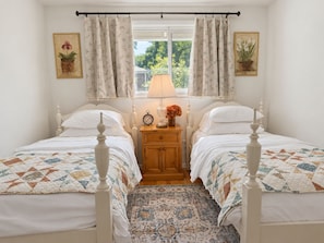 A bedroom with two single beds, a nightstand with a lamp, a clock, and a vase of flowers. - Bluebell Cottage, Walkable Fall City Stay w/ Hot Tub & Fenced Yard, Pets Welcome (Fall City)