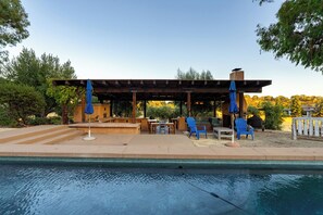 A poolside area with a pergola, outdoor seating, and umbrellas. - Gorgeous 5BR Spanish Villa w/Pool & Spa in Paso Wine Country (Paso Robles)