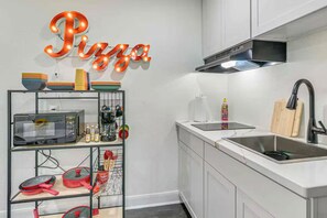 A kitchen with a microwave, sink, and a shelf with kitchen utensils. - 3 minutes from pleasure pier near beaches (Galveston)