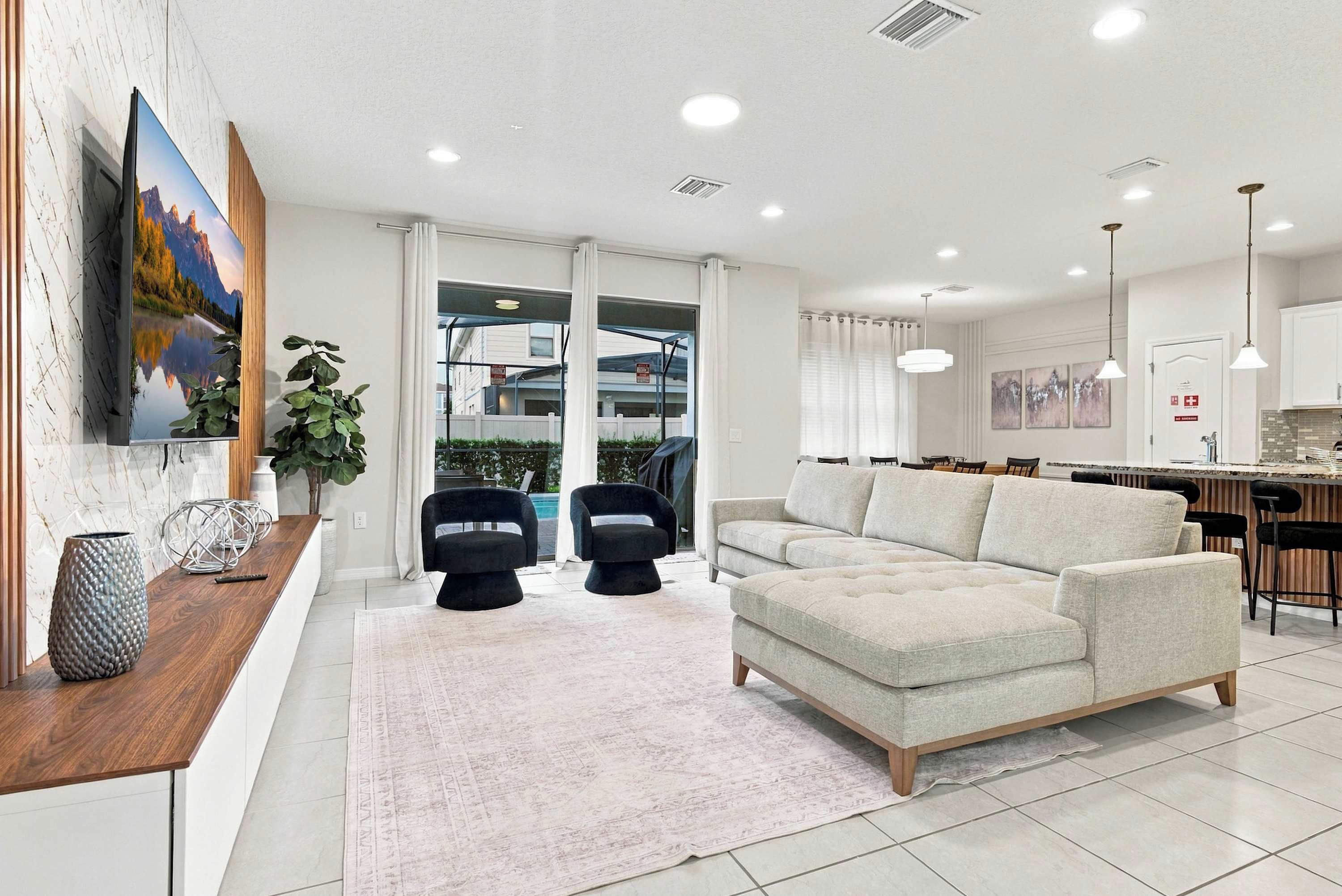 A modern living room with a sofa, two black chairs, a coffee table, and a large painting on the wall.