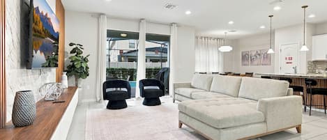 A modern living room with a sofa, two black chairs, a coffee table, and a large painting on the wall.