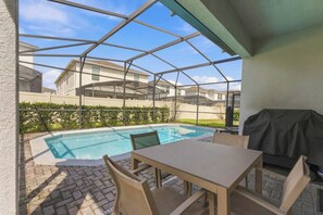 A covered outdoor area with a pool, a table, and chairs. - 2472 Toy Barn Slide Bed & Game Room! Private Pool (Kissimmee)