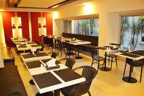 Um restaurante com várias mesas e cadeiras, algumas com menus e guardanapos.