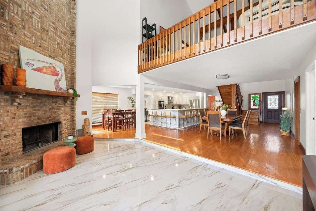 A spacious living area with a fireplace, a dining area, and a kitchen in the background.