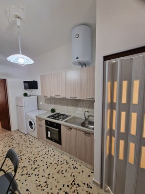 A compact kitchen with a washing machine, a stove, and a sink. - Cozy apartment in the heart of Trapani's historic center, near the harbor (Trapani)