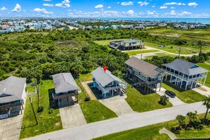 A residential area with multiple houses, a clear sky, and a view of the ocean. - Canal Views~Fire Pit Nights~Cornhole Fun~Pets (Galveston)