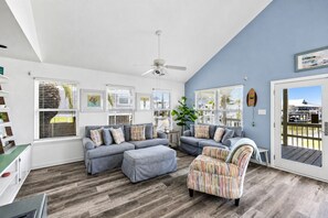 A living room with a sectional sofa, a striped armchair, and a ceiling fan. - Canal Views~Fire Pit Nights~Cornhole Fun~Pets (Galveston)
