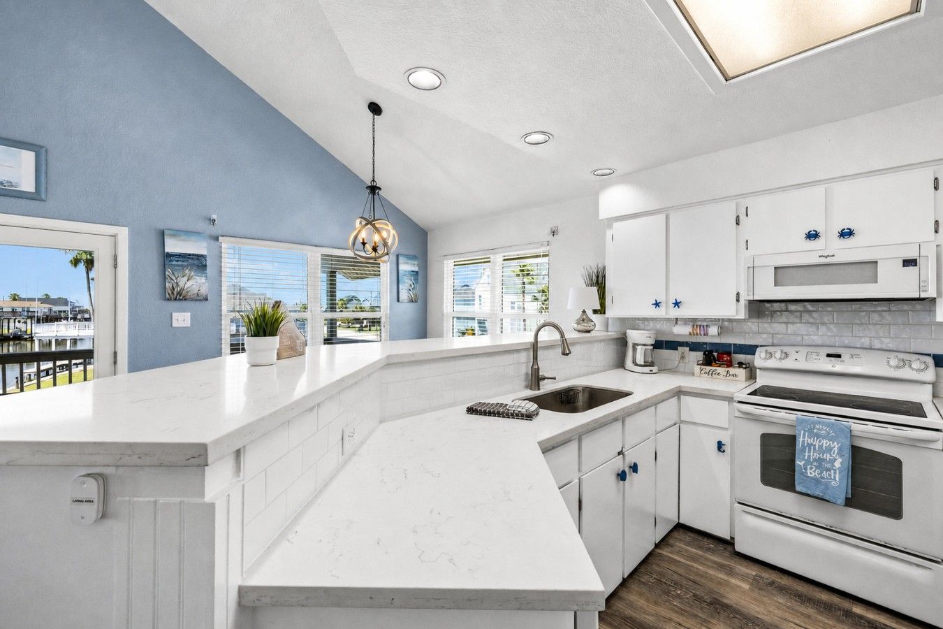 A modern kitchen with white cabinetry, a large island, and a view of the outdoors.