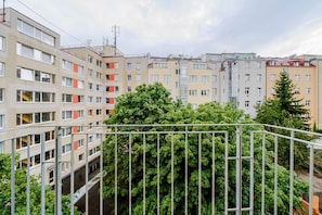 A multi-story residential building with balconies and a dense green tree in the foreground. - Blueground | Nusle, balcony, well-connected, cafes (PRG-77) (Prague)