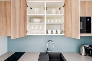 A modern kitchen with a built-in dishwasher, a stainless steel kettle, and a black sink. - Blueground | Nusle, balcony, well-connected, cafes (PRG-77) (Prague)
