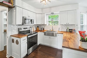 A modern kitchen with white cabinets, a stainless steel oven, a microwave, and a wooden countertop. - Erlanger 4BR Hot Tub, Pool Table Sleeps 10 (Erlanger)