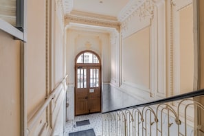 A grand hallway with a marble floor, ornate wall decorations, and a staircase with a metal railing. - Blueground | New Town, view, nr Vltava River (PRG-125) (Prague)
