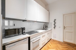 A modern kitchen with white cabinetry, a built-in microwave, a coffee machine, and a stainless steel sink. - Blueground | New Town, view, nr Vltava River (PRG-125) (Prague)
