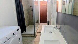 A compact bathroom with a shower, a sink, and a washing machine. - Chalet in the middle of the woods, ARCACHON BAY (Gujan-Mestras)