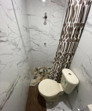 Een badkamer met toilet, douche en marmeren wanden.