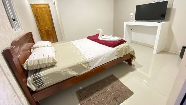 Quarto com cama, televisão em móvel, ar-condicionado e uma porta.