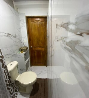 Un baño con inodoro, lavamanos y zona de ducha.