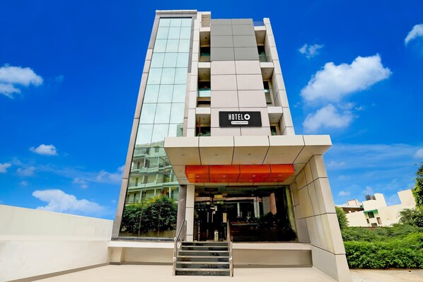 A modern hotel building with a prominent 'HOTELO' sign, a glass facade, and a staircase leading to the entrance.
