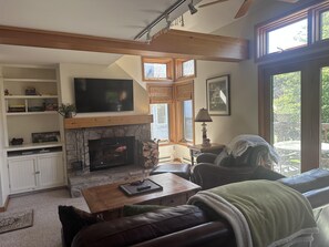 A cozy living room with a fireplace, a television, and a comfortable seating area. - Sunny, Quiet Condo on Golf Course near Mount Snow and Hermitage Resorts (Wilmington)
