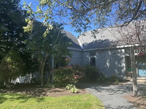 A residential property with a covered porch, a front door, and a small garden area with shrubs and a tree.
