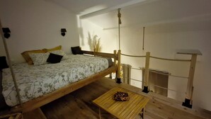 A room with a bed, a small table, and a wooden railing. - Suite with a private hot tub (Pierrelatte)
