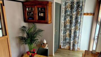Ein Essbereich mit Holztisch, Stühlen, einer Blumenvase, einem Schrank und einem Fenster mit Vorhängen.
