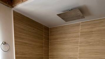 Une salle de bain moderne avec une baignoire sur pieds, des murs recouverts de panneaux en bois, une petite table ronde ornée d’un vase et une échelle en bois.
