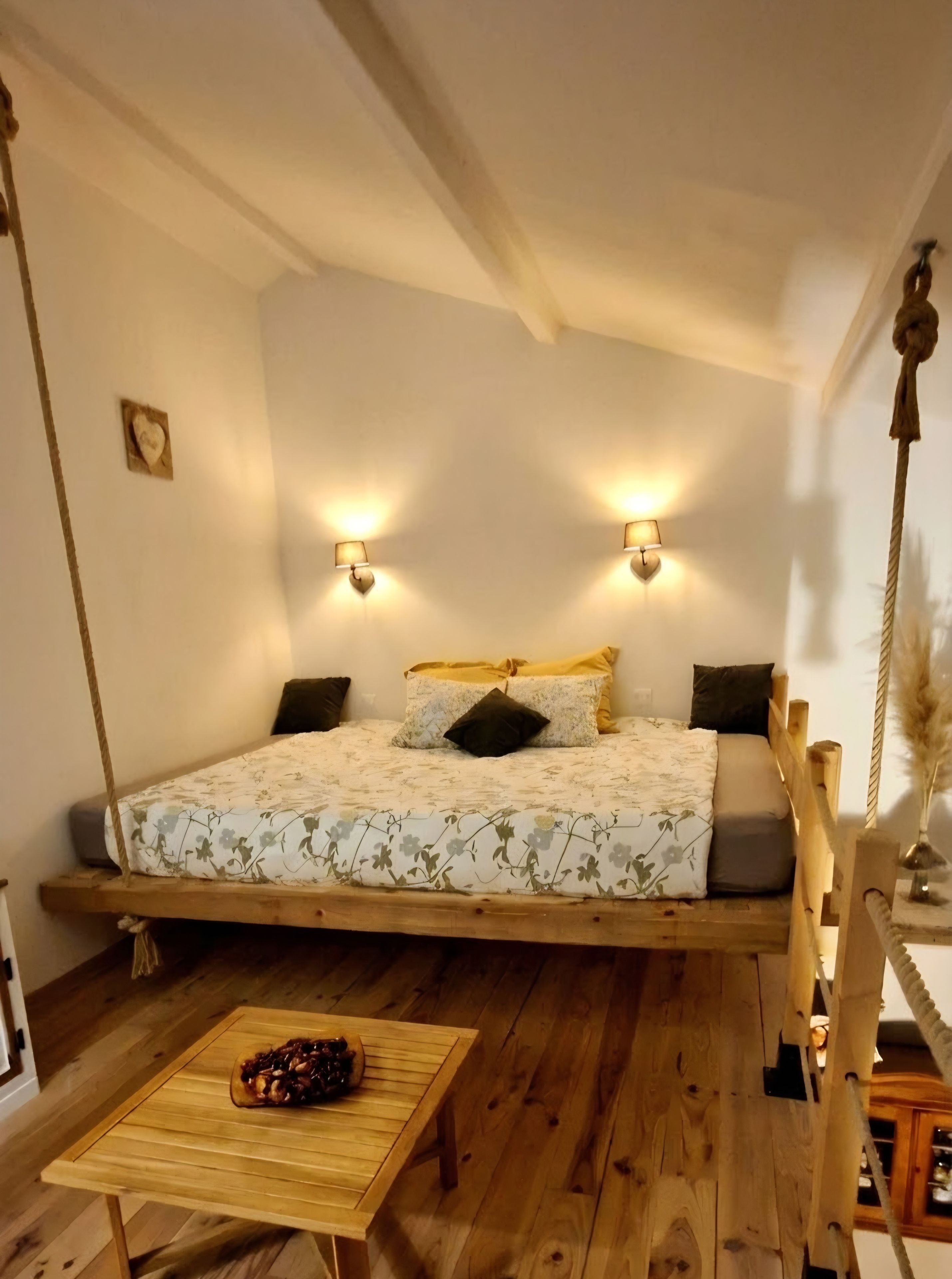 Une pièce confortable avec un lit, une petite table et un fauteuil suspendu.