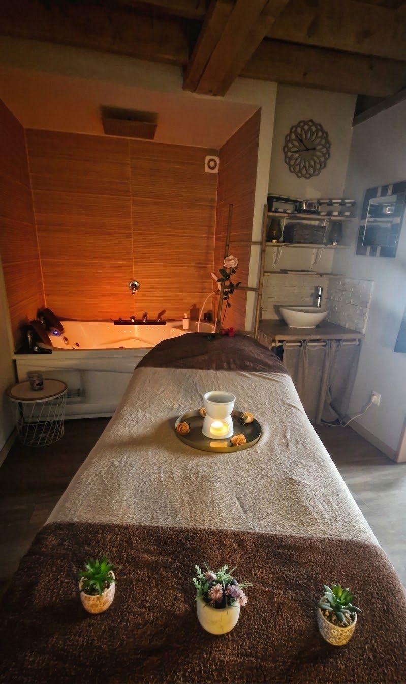Une salle de spa équipée d’une table de massage, d’une baignoire et d’un petit lavabo.