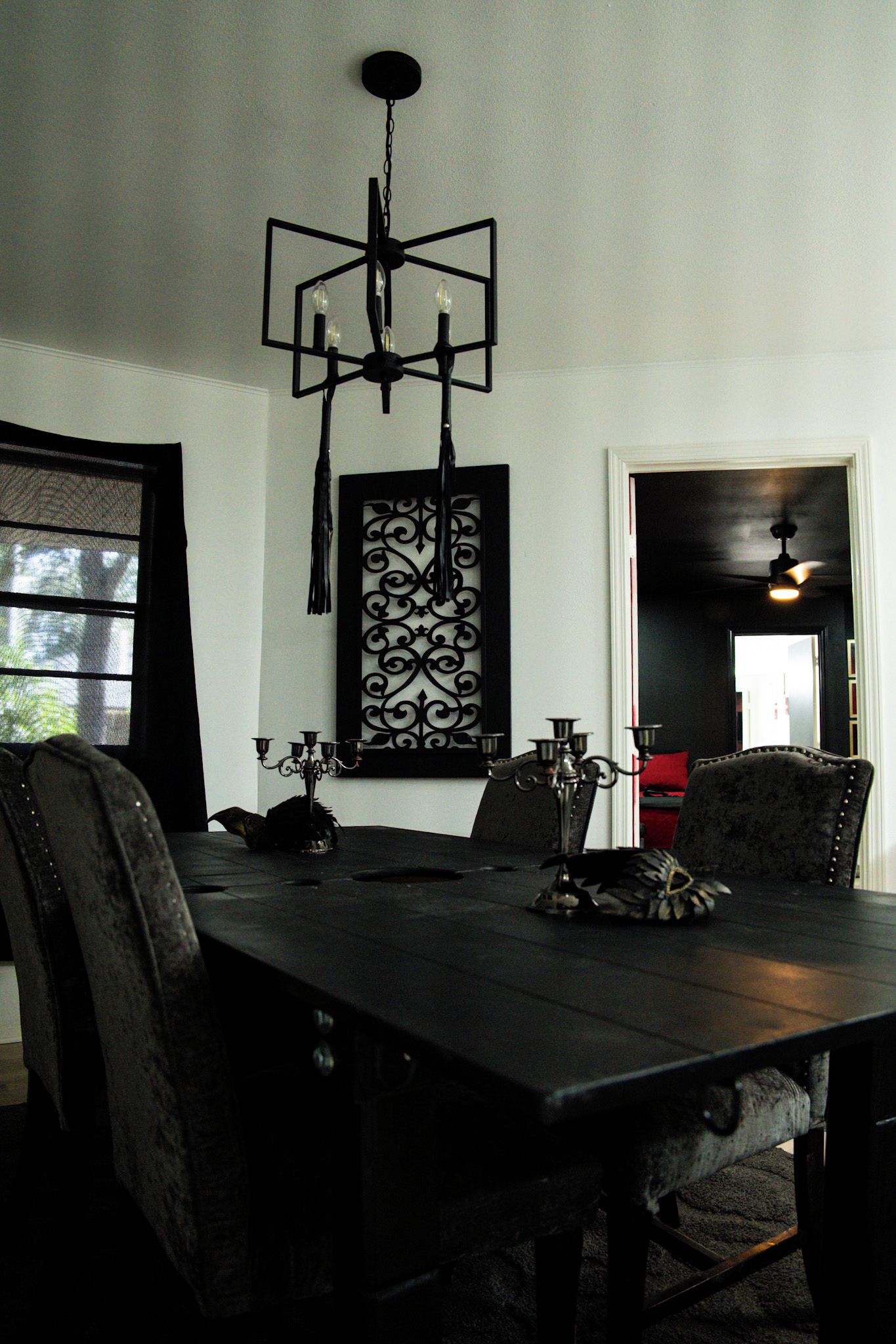 Uma sala de jantar com uma mesa de madeira escura, cadeiras pretas e um candelabro.