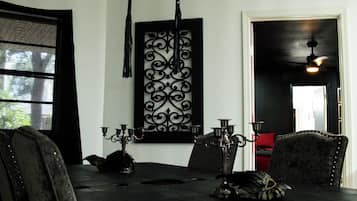 Uma sala de jantar com uma mesa de madeira escura, cadeiras pretas e um candelabro.
