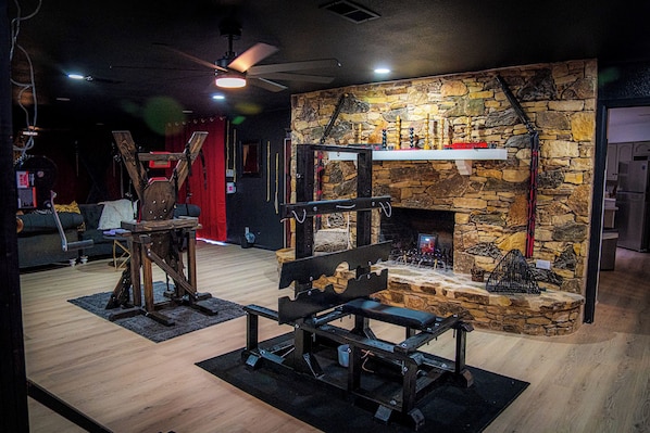 A room with a stone fireplace, a wooden bench, and a red curtain.