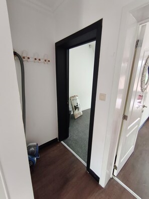 A hallway with a black-framed door leading to a room, a blue exercise machine, and a trash bin. - Adorable apartment in nice Leuven perfect for your city stay (Leuven)