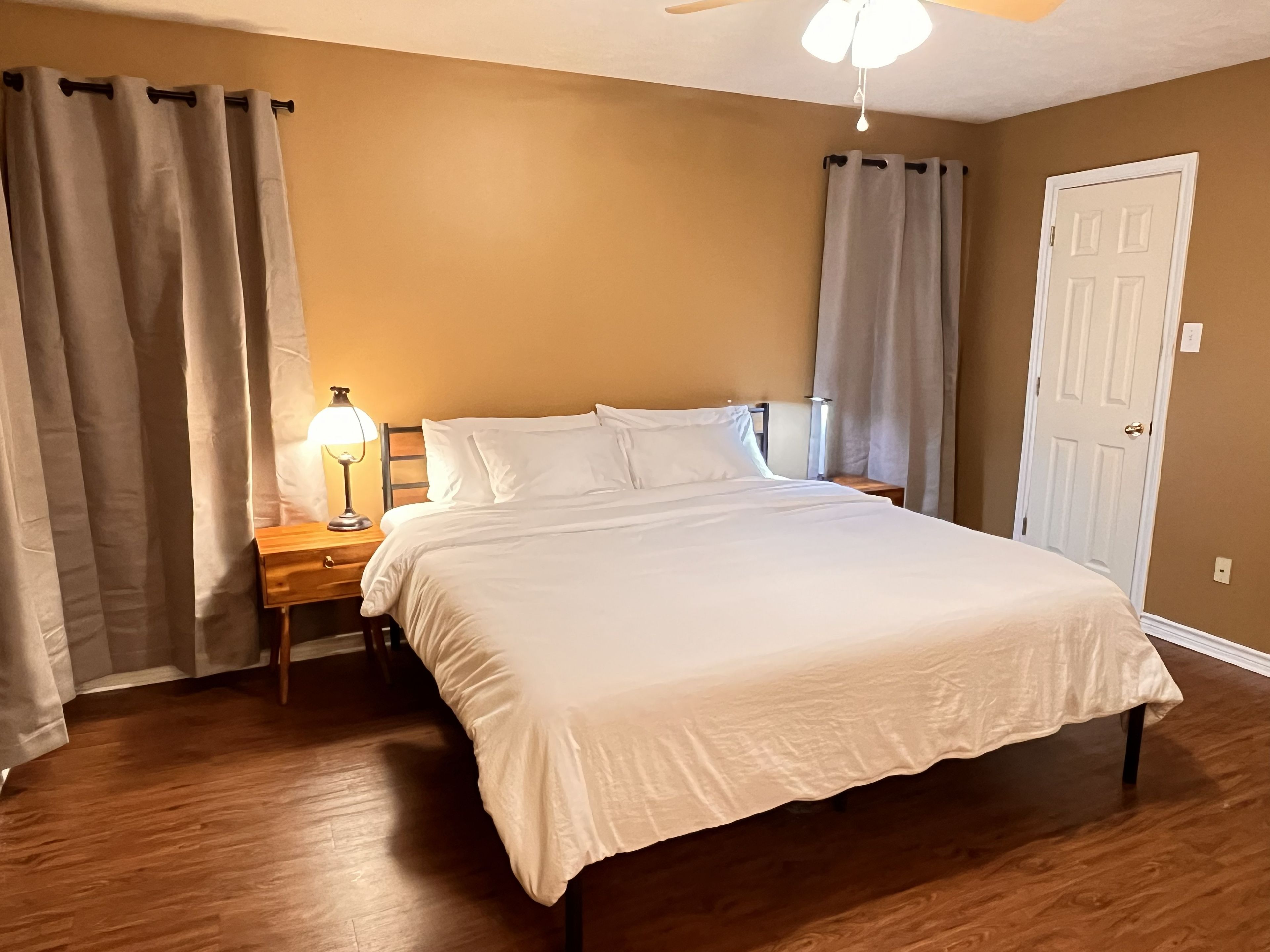 Une chambre à coucher avec un lit, une table de chevet, une lampe et une porte.