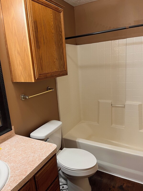 Une salle de bain équipée de toilettes, d’un lavabo, de meubles en bois et d’une baignoire.