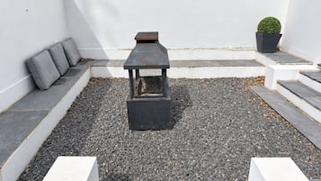 Une terrasse sur le toit avec un banc en pierre, une petite table et un pot de fleurs.