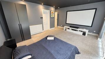 A bedroom with a bed, a TV, a white bench, and a door.