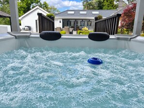 A hot tub with a blue float, surrounded by a white pool deck, with a house in the background.