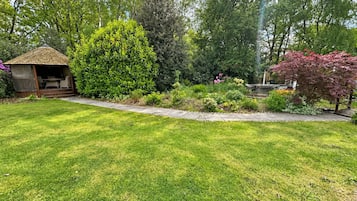A well-maintained garden with a gazebo, various shrubs, and a lawn.