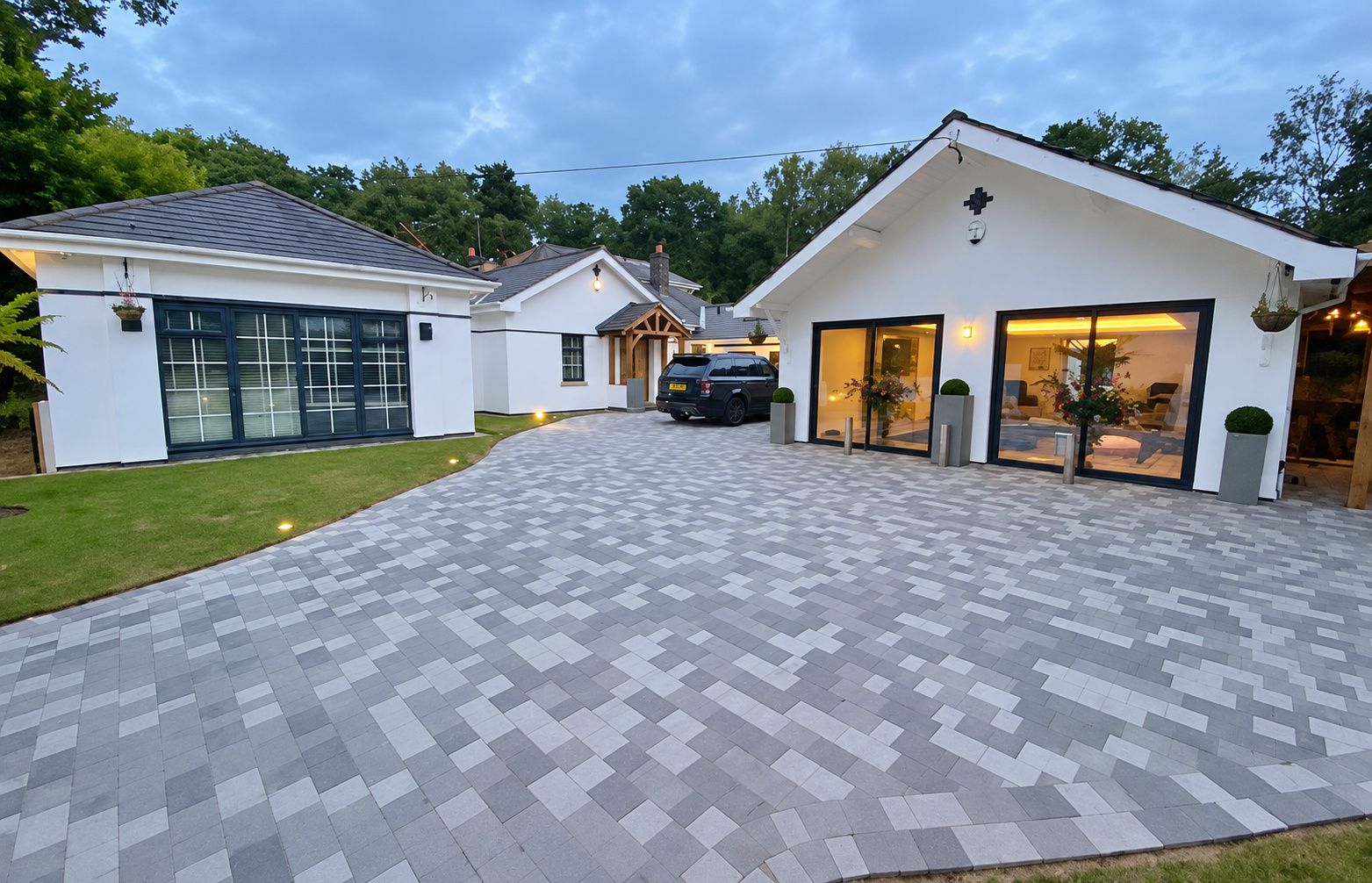 Ein modernes Haus mit befestigter Auffahrt, die zu einer Garage und einem großzügigen Eingang mit Fenstern führt.