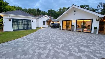 Ein modernes Haus mit befestigter Auffahrt, die zu einer Garage und einem großzügigen Eingang mit Fenstern führt.