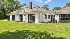A two-story house with a covered porch, large windows, and a chimney. - Mereside House | Heated Indoor Pool, Hot Tub & Cinema (Allostock)