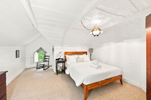 A bedroom with a wooden bed, a nightstand, a lamp, a rocking chair, and a window with a view. - Vintage Charm, Backyard, WiFi, Near Dtwn Decatur (Decatur)