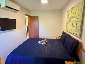 Ein Schlafzimmer mit einem Bett, einem Flachbildfernseher, einer Tür und einem Gemälde an der Wand.
