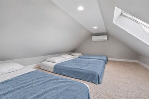 Ein Schlafzimmer mit zwei Betten, einem Dachfenster und einer Klimaanlage.