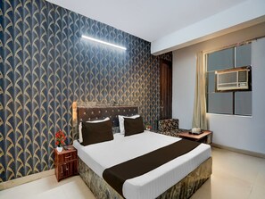 Une chambre d’hôtel avec un grand lit, une table de chevet, une chaise et une fenêtre équipée d’un appareil de climatisation.