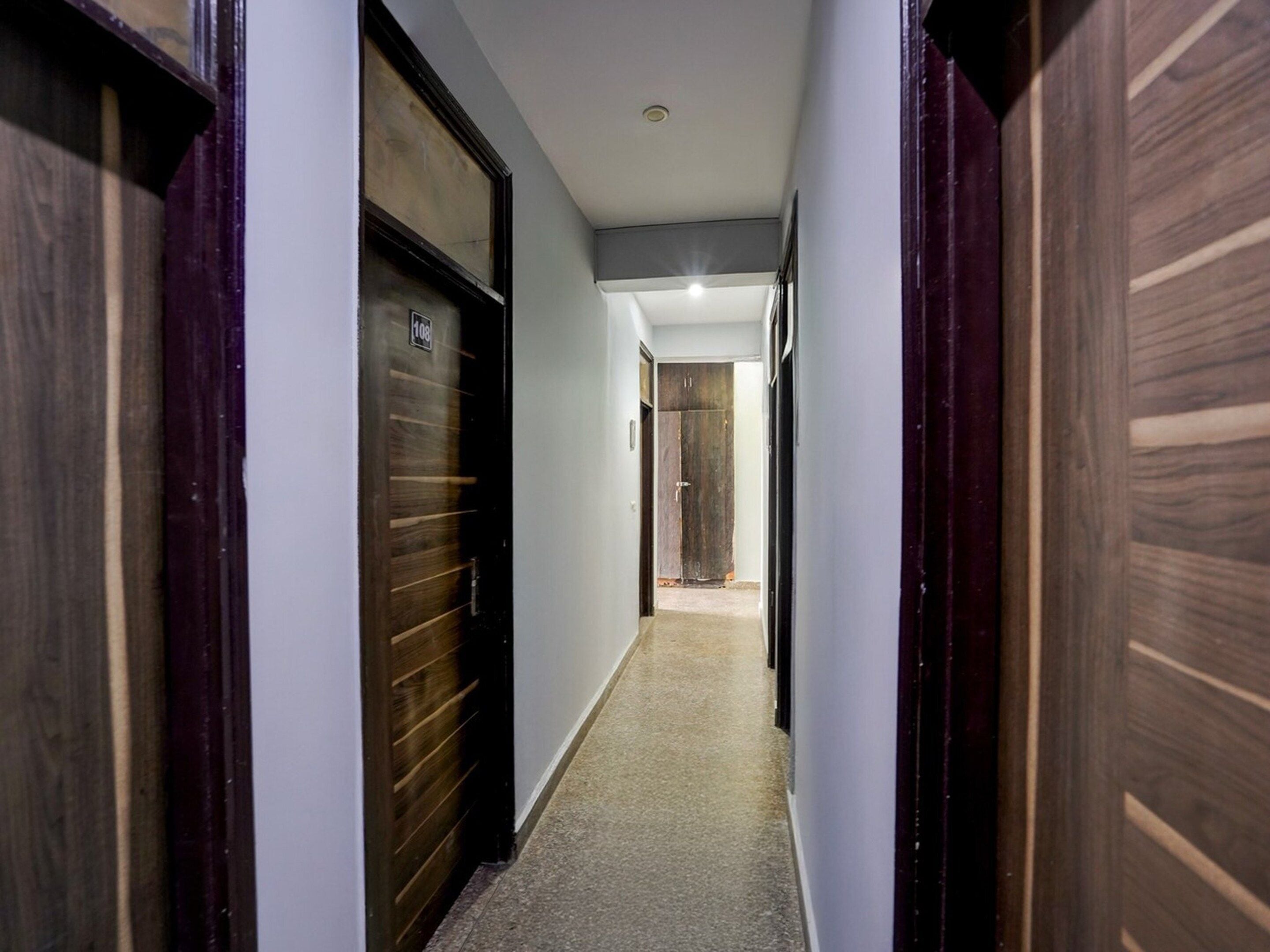 A narrow hallway with wooden doors and a carpeted floor.