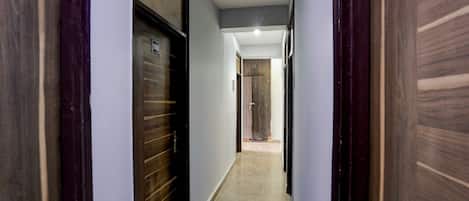 A narrow hallway with wooden doors and a carpeted floor.