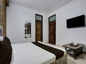 A hotel room with a bed, a small table, a TV, and two doors. - Classic With Balcony The Cloud inn Hotel Grand (Ghaziabad)