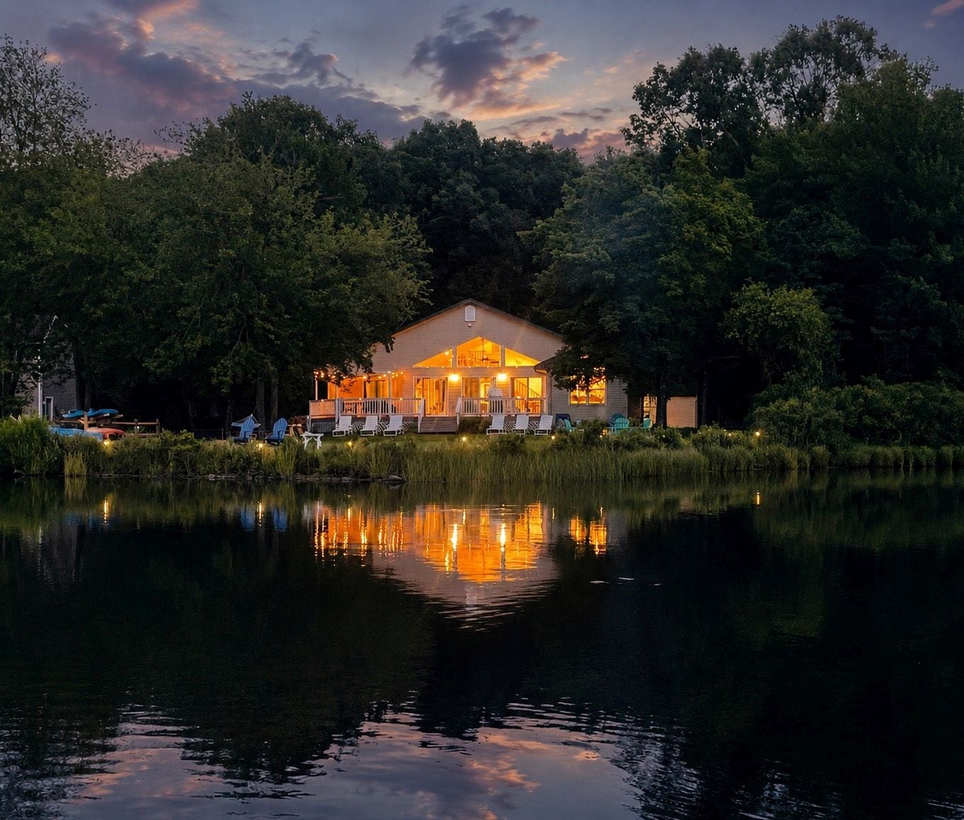 A lakeside lodge with a reflective water surface, surrounded by dense trees.